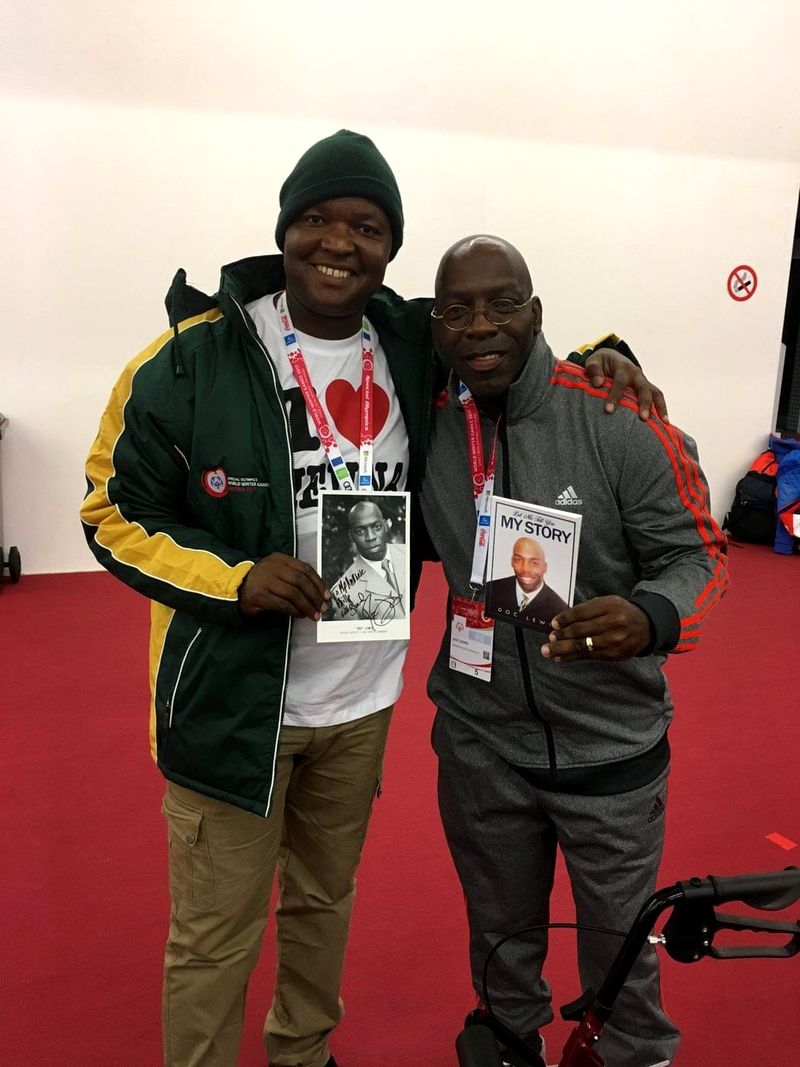 Doc Lewis holding his book beside a smiling friend at the Special Olympics World Winter Games in Austria