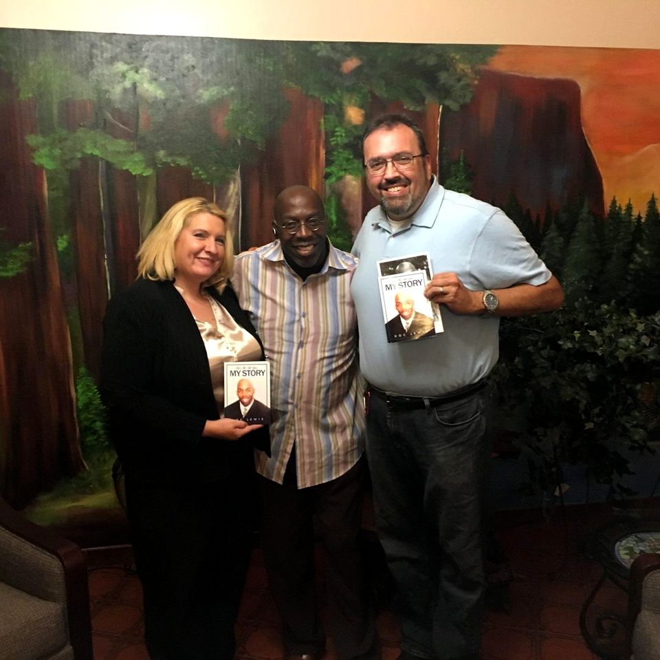 Doc Lewis with two friends who are each holding a copy of his book