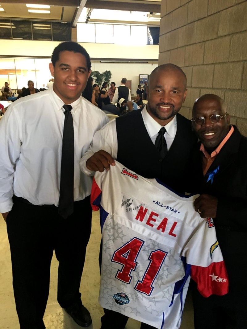Doc Lewis with two friends holding up a signed all-star football jersey