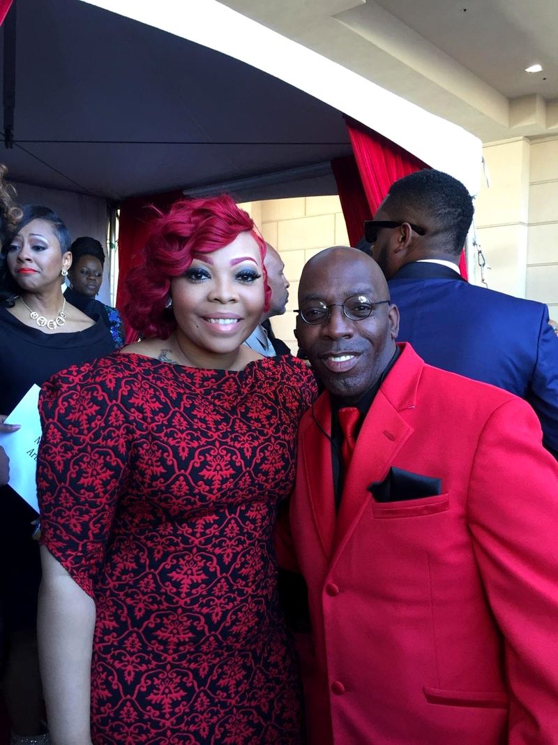 Doc Lewis in a red jacket with a friend in a red patterned dress