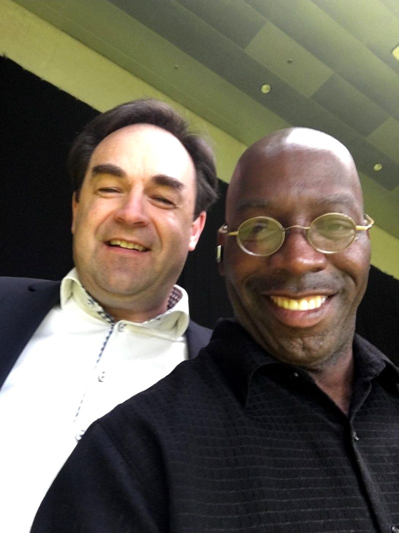A smiling selfie of Doc Lewis in round glasses with a friend