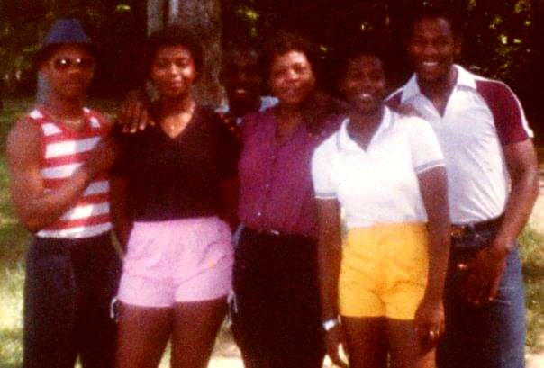 An older snapshot of a group of family and friends posing together outdoors