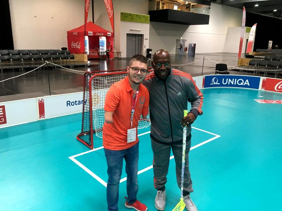 Doc Lewis with a young man in front of a floorball court at the Games in Austria