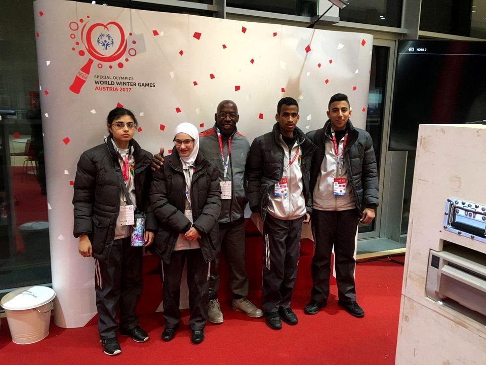 Doc Lewis with a group of athletes in front of the World Winter Games backdrop