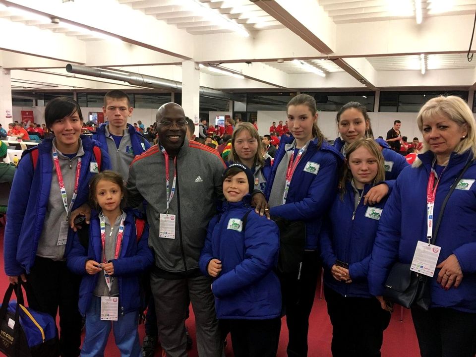 Doc Lewis with a group of young athletes and coaches in blue jackets