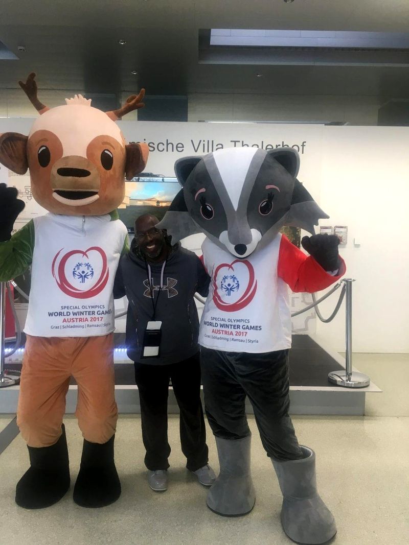 Doc Lewis between two costumed mascots of the Special Olympics World Winter Games, Austria 2017