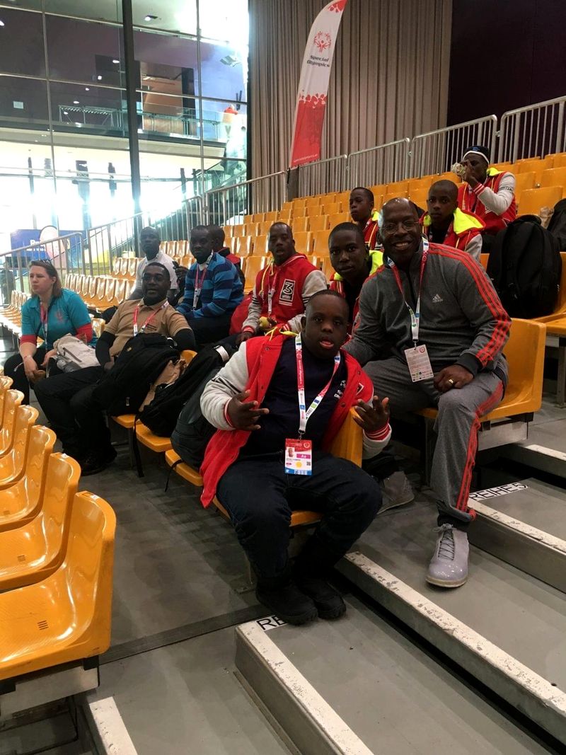 Doc Lewis sitting with athletes and fans in the stands at the Games