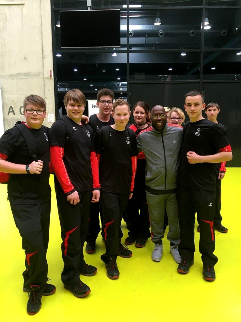 Doc Lewis with a team of young athletes in matching black and red jackets