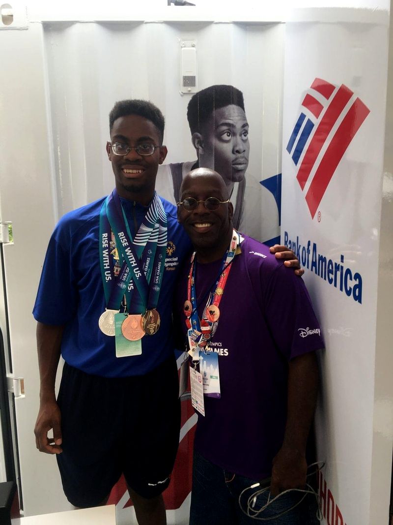 Doc Lewis with an athlete wearing three medals