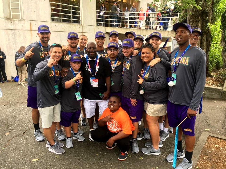 Doc Lewis with a team of athletes and coaches in purple and grey
