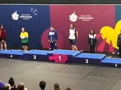 Athletes on a numbered medal podium at a Special Olympics World Games ceremony, with World Games banners behind them